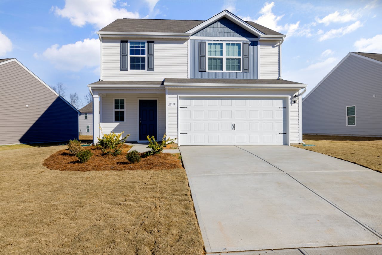 A modern suburban house with a clean aesthetic, showcasing a two-car garage and lush front yard.