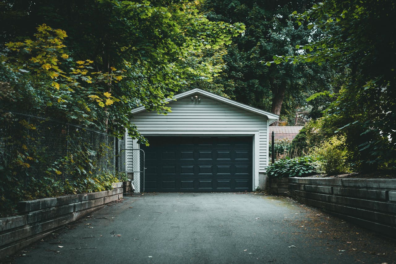 A scenic garage with lush greenery and a driveway, perfect for residential and nature-themed content.